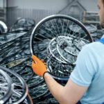 154526765-mecânico-no-uniforme-segura-a-roda-da-bicicleta-na-fábrica