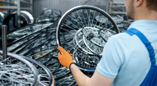 154526765-mecânico-no-uniforme-segura-a-roda-da-bicicleta-na-fábrica